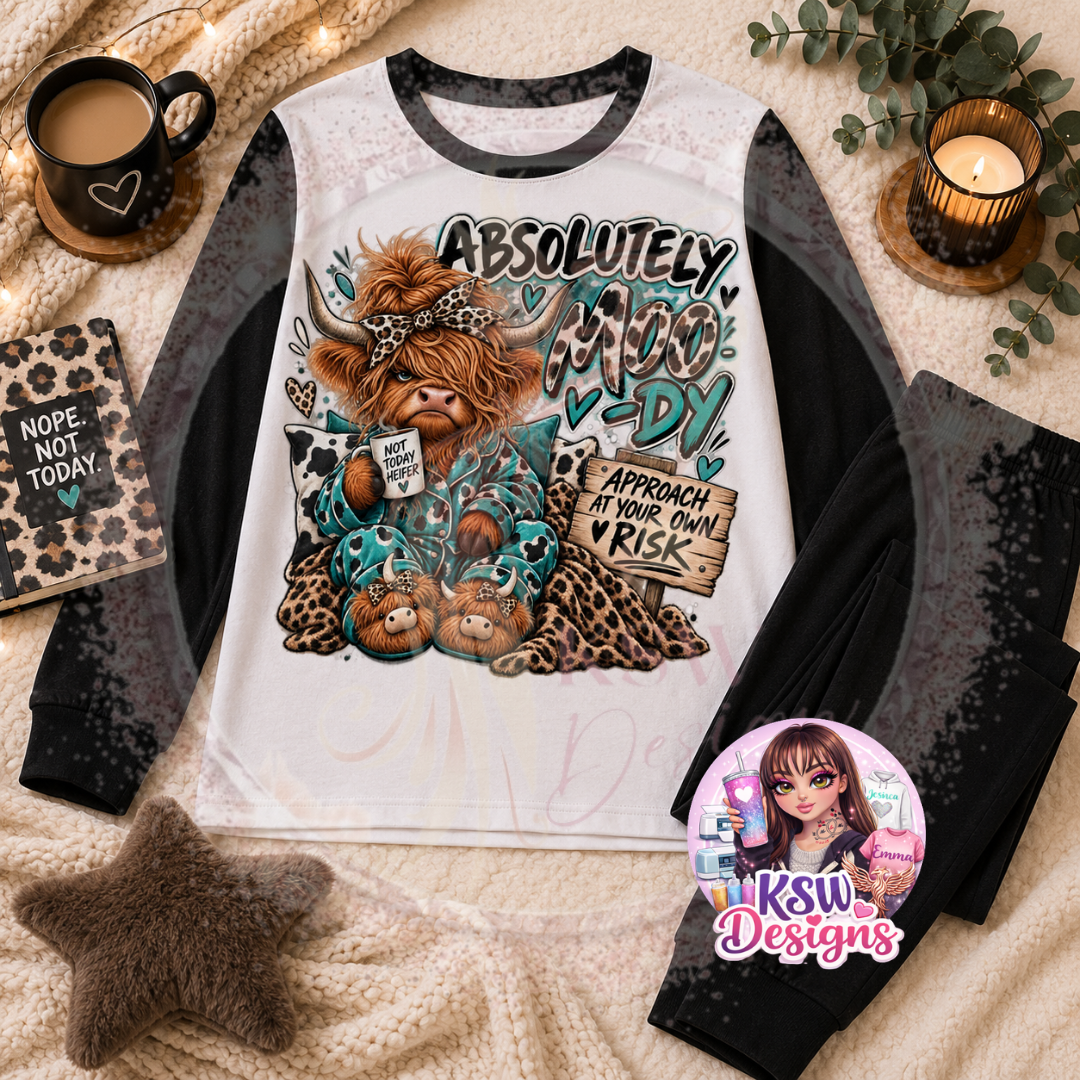 Absolutely Moo-dy Highland cow adult pyjama set featuring a cosy cow with slippers, mug and animal print details, shown on black block pyjamas