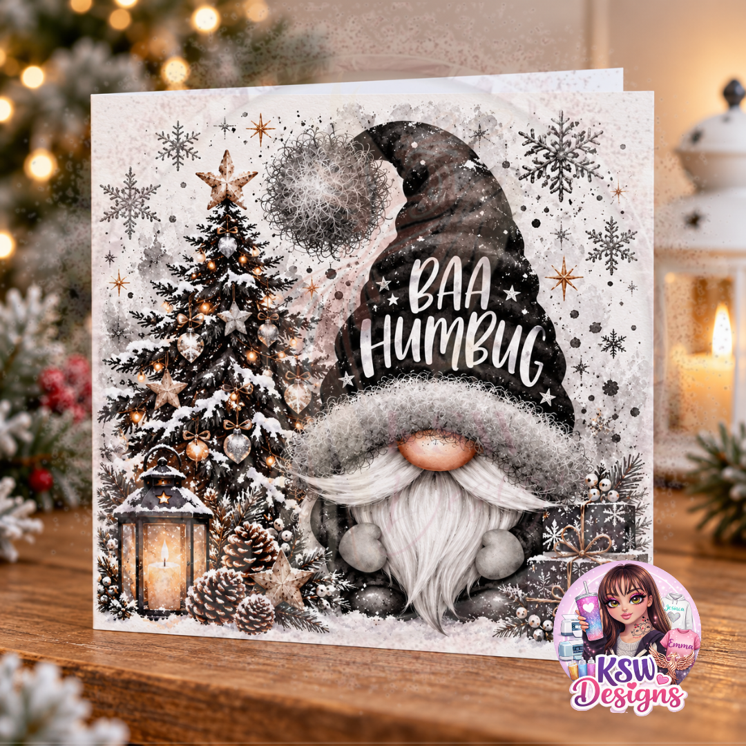 Square Christmas greeting card featuring a white-bearded gonk wearing a black Baa Humbug hat, beside a snowy Christmas tree, glowing lantern and wrapped presents.
