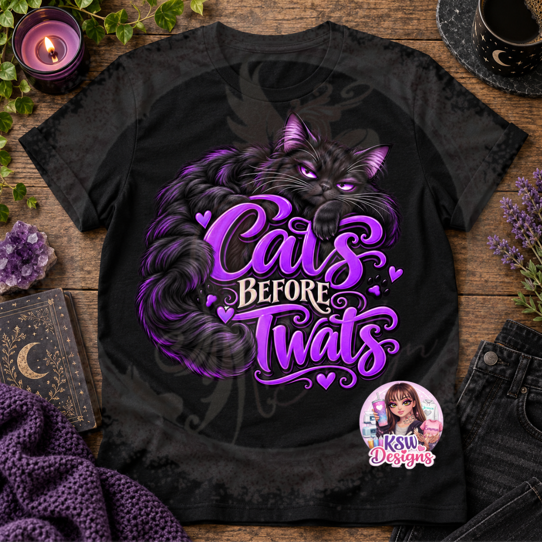 Black t-shirt featuring a fluffy black cat with purple eyes and bold Cats Before Twats lettering in purple and white, displayed as an alternative cat lover graphic tee.