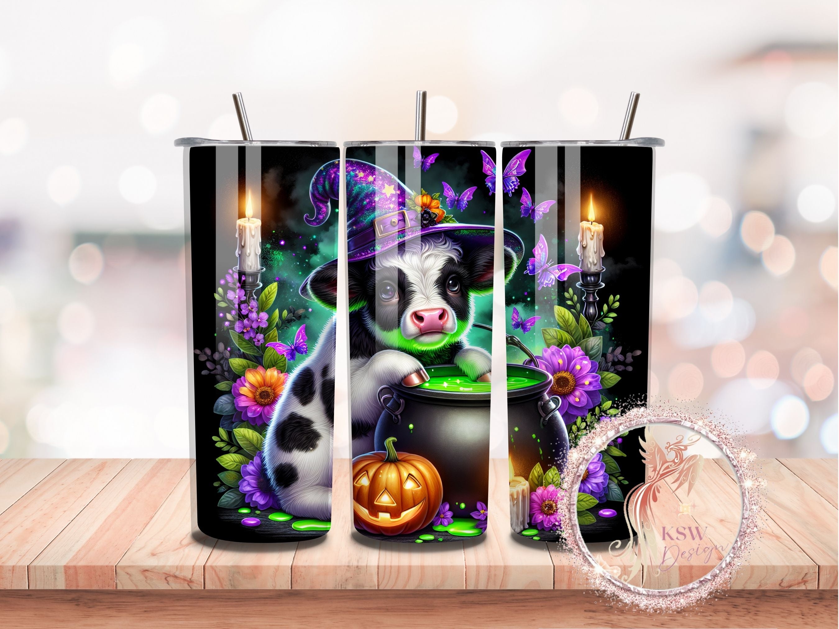 Tumbler with a cow in a witch hat and cauldron design on a wooden surface.