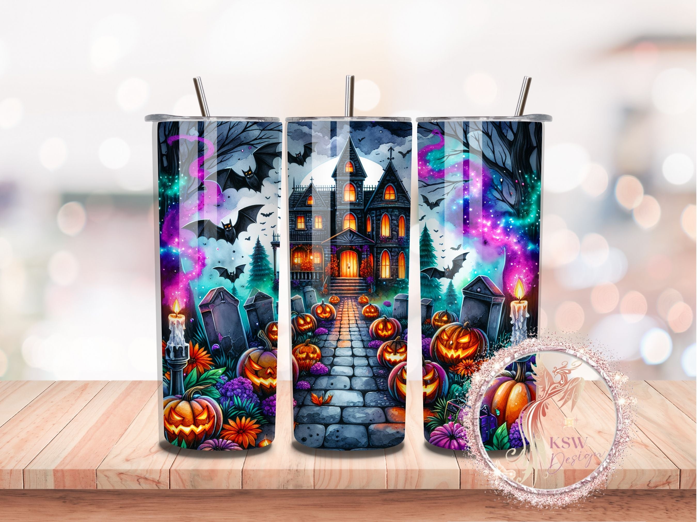 Three Halloween-themed tumblers with a haunted house design on a wooden surface.