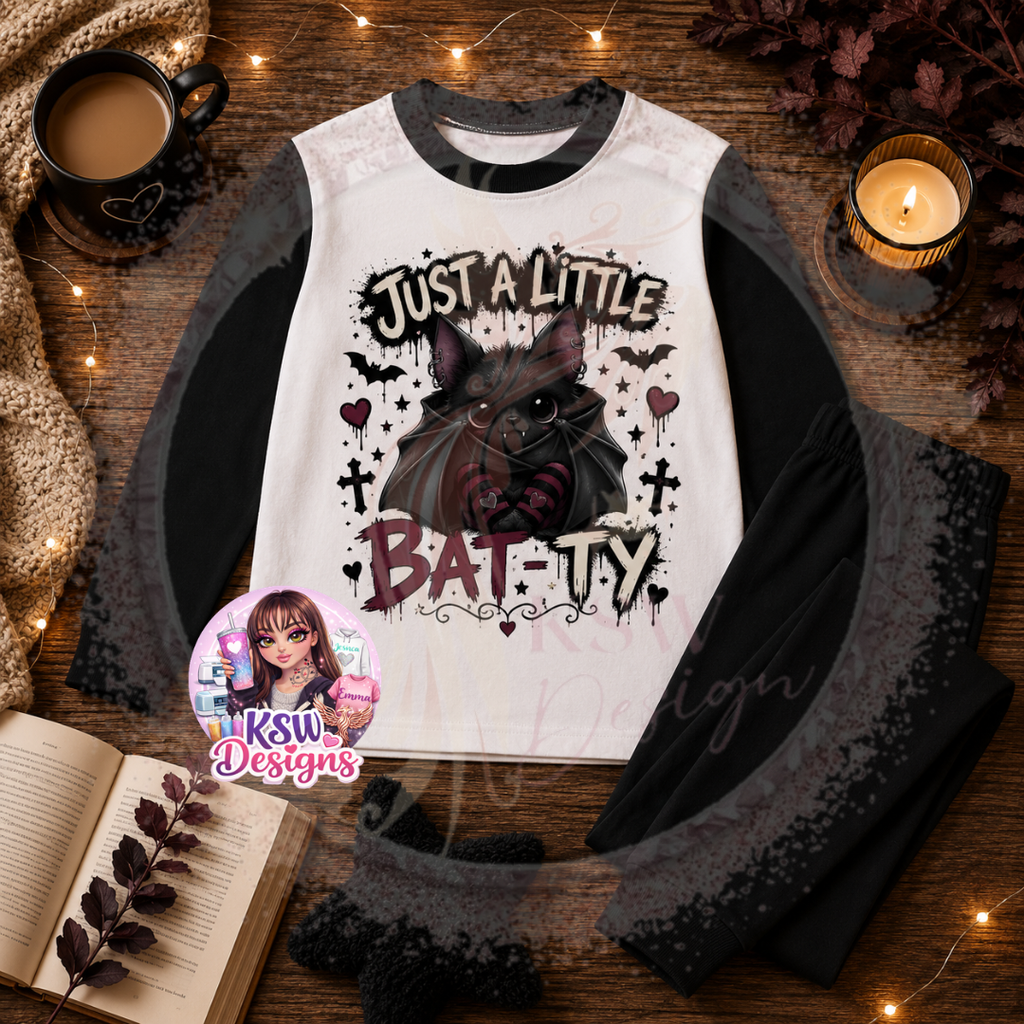 Just A Little Batty adult pyjama set featuring a cute black gothic bat with striped details, crosses, hearts and stars shown on black block pyjamas