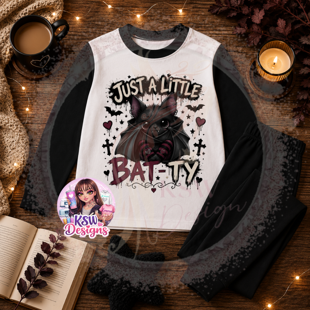 Just A Little Batty adult pyjama set featuring a cute black gothic bat with striped details, crosses, hearts and stars shown on black block pyjamas