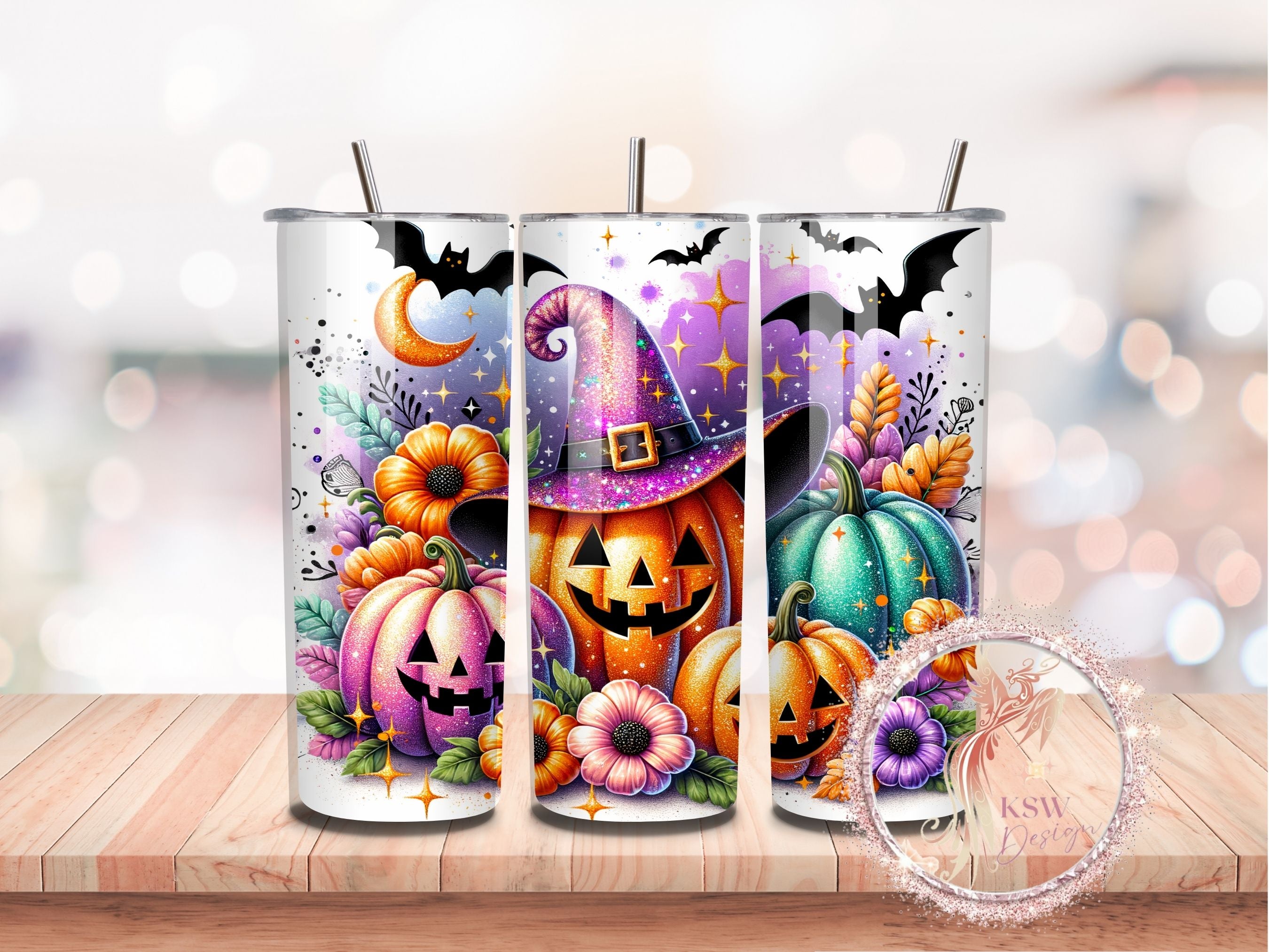 Three Halloween-themed tumblers with pumpkins, bats, and witch hats on a wooden surface.