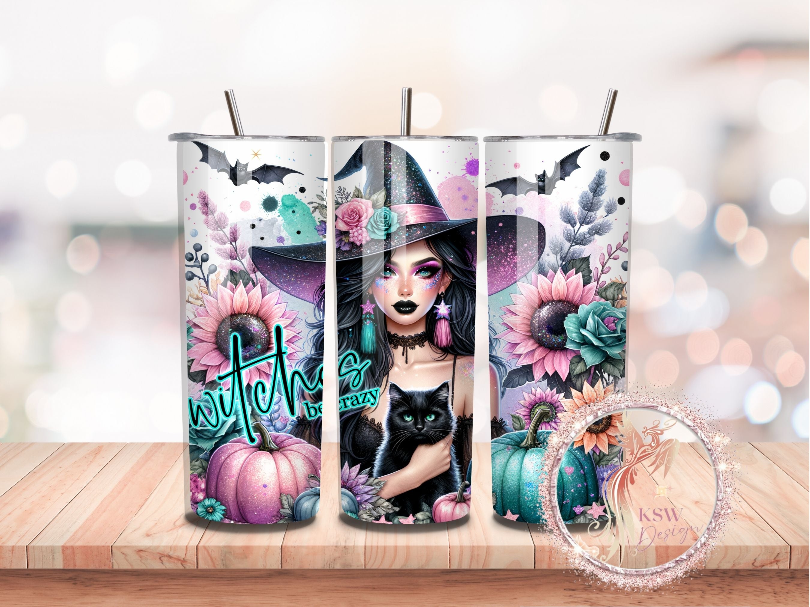 Three tumblers with witch-themed designs featuring pumpkins, flowers, and a cat on a wooden surface.